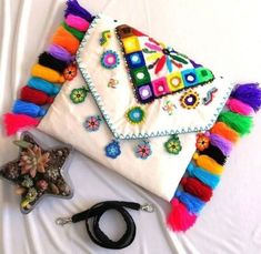 a white purse with multi colored tassels and a star decoration on the side