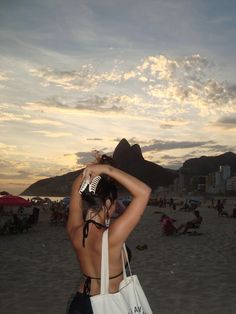 a woman standing on top of a sandy beach holding a white bag over her head