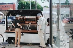 two people standing at a food truck on the street