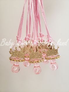 a pink chandelier hanging from a ceiling with gold trimmings and princess crowns on it