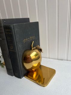 an apple shaped bookend sitting on top of a table next to a black book