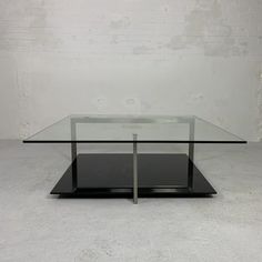 a glass and metal coffee table in the shape of a rectangle with two legs