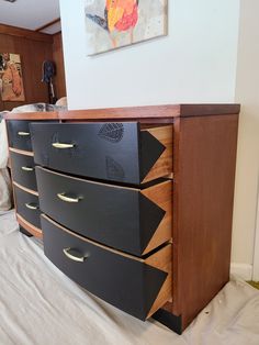 a black and brown dresser sitting on top of a bed