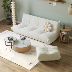 a living room with a white couch, coffee table and potted plant on the floor