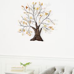 a living room with a white couch and a tree wall hanging on the wall