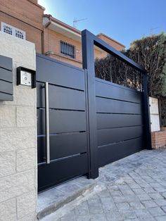 two black gates are open in front of a brick building