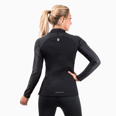 a woman wearing a black wetsuit with her hands on her hips and looking back