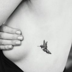 a black and white photo of a hummingbird on the side of a woman's stomach