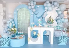 a blue and white birthday party with balloons, decorations and desserts on the table