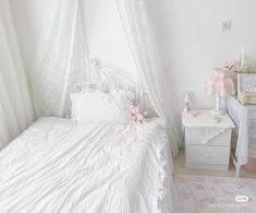 a white bed sitting in a bedroom next to a dresser and table with a teddy bear on it