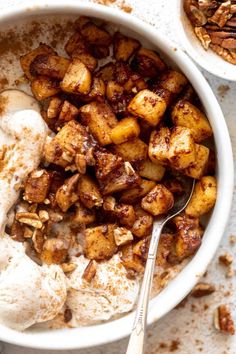 two bowls filled with food on top of a white table next to pecans and nuts