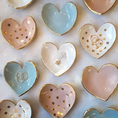 many heart shaped dishes with gold dots and rings in them on a white tablecloth