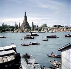 many boats are in the water near some buildings and a large spire is in the background