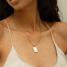 DESCRIPTION & DETAILS Easy to layer and wear every day, this tag necklace is an edgy personal touch to your stack. This necklace features a rectangular tag with beautiful white stone in the center. Plating: 14k Gold Materials: 14K Gold on Stainless Steel, AAA Freshwater Pearl Measurements: Chain Length: 44+5cm, Pendant: 22mm+15mm Hypoallergenic SUSTAINABILITYIn-house plating - All pieces are hand crafted by our in-house jewellers ensuring a high standard of working conditions.Fair pricing - Due Modern White Chain Necklace For Everyday, Trendy White Chain Necklace For Layering, Everyday White Tarnish Resistant Chain Necklace, Minimalist White Pendant Chain Necklace, Minimalist White Charm Necklaces For Layering, White Rectangular Necklace For Everyday, Rectangular Charm Necklaces For Everyday, Everyday White Rectangular Pendant Necklace, Gold Necklaces With Rectangular Stone