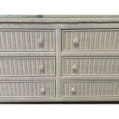 a white wicker dresser with four drawers and one drawer on the bottom, in front of