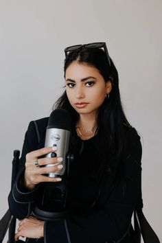 a woman holding a microphone in her right hand and wearing sunglasses on top of her head