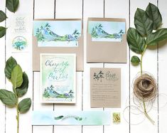 the wedding stationery is laid out with greenery