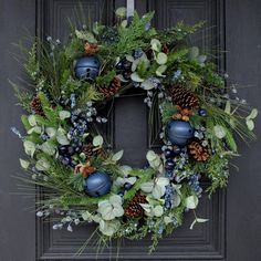 a wreath with pine cones and blue berries