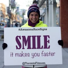 a woman holding a sign that says smile it makes you faster