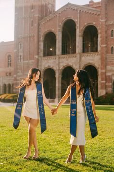 two women in graduation gowns holding hands