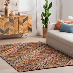 a living room with a couch, rug and potted plant