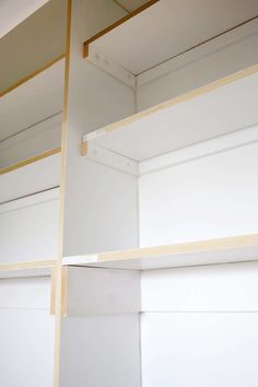 the inside of a closet with white walls and wood trimmings on the shelves