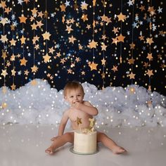 a baby sitting in front of a cake with stars on it