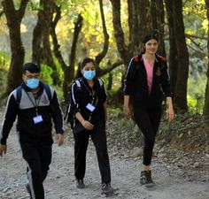 three people walking down a trail wearing masks