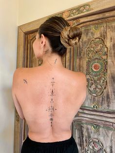 the back of a woman's body with tattoos on her upper and lower back