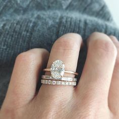 a woman's hand with two wedding bands and a diamond ring on her finger