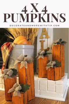 four pumpkins sitting on top of a wooden block next to a canister filled with hay