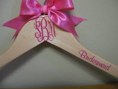 a wooden hanger with a pink bow and monogrammed initials