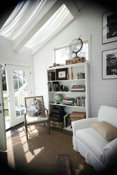 a living room filled with furniture and bookshelves next to a doorway that leads to a patio