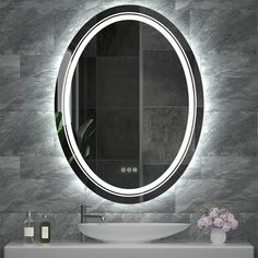 a bathroom sink with a lighted mirror above it and a vase on the counter next to it