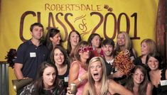 a group of people standing next to each other in front of a yellow sign that says robertsdale class & amp 2011