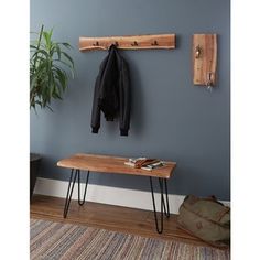 a coat rack with two coats hanging on it next to a bench and potted plant