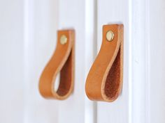 a pair of leather handles on a white door