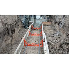 construction workers are working on the side of a road that has been dug in dirt