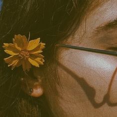 a close up of a person wearing glasses with a flower in their hair and eyeglasses