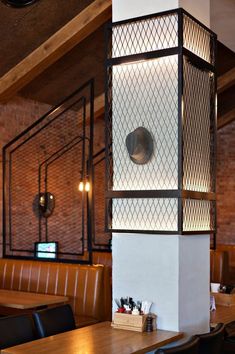 a restaurant with wooden tables and black leather chairs in front of a tall white pillar