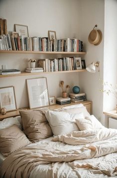 an unmade bed in a bedroom with bookshelves and pictures on the wall