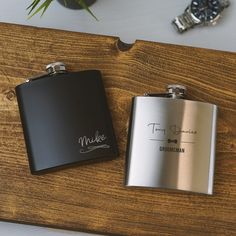 two stainless steel flasks sitting on top of a wooden table