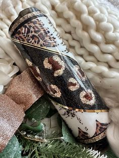 a decorative vase sitting on top of a pile of white flowers and greenery next to a knitted blanket