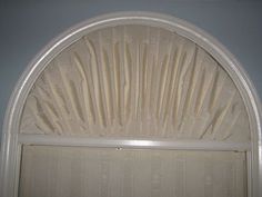 an arched window with white curtains on it