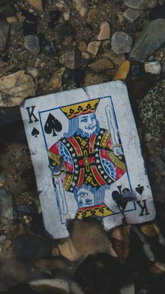 a playing card laying on the ground surrounded by rocks