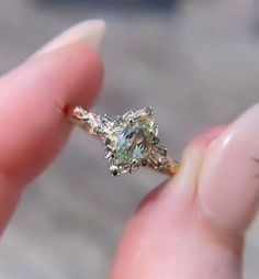 a person is holding a ring with an aqua and white diamond in it