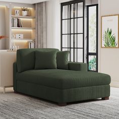 a living room with a large green couch in the center and a book shelf behind it