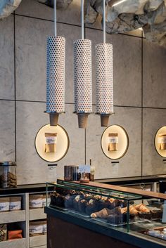 three lights hanging from the ceiling above a bakery counter filled with pastries and muffins