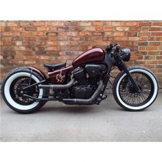 a maroon motorcycle parked next to a brick wall