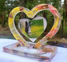 a heart shaped glass photo frame with a horse in the middle on top of a table